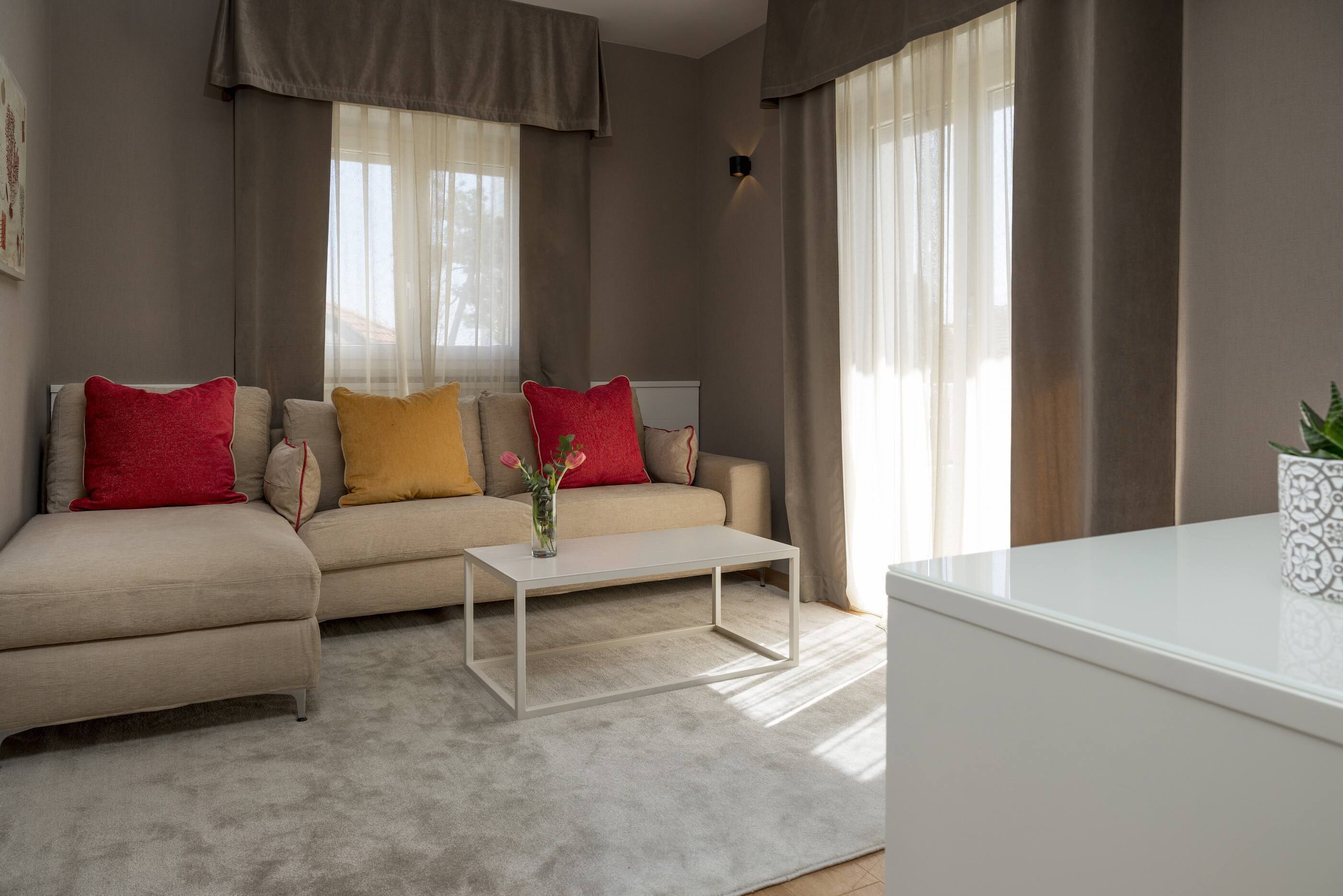 A modern living room with a beige sofa, a white coffee table, and a small side table with a plant.