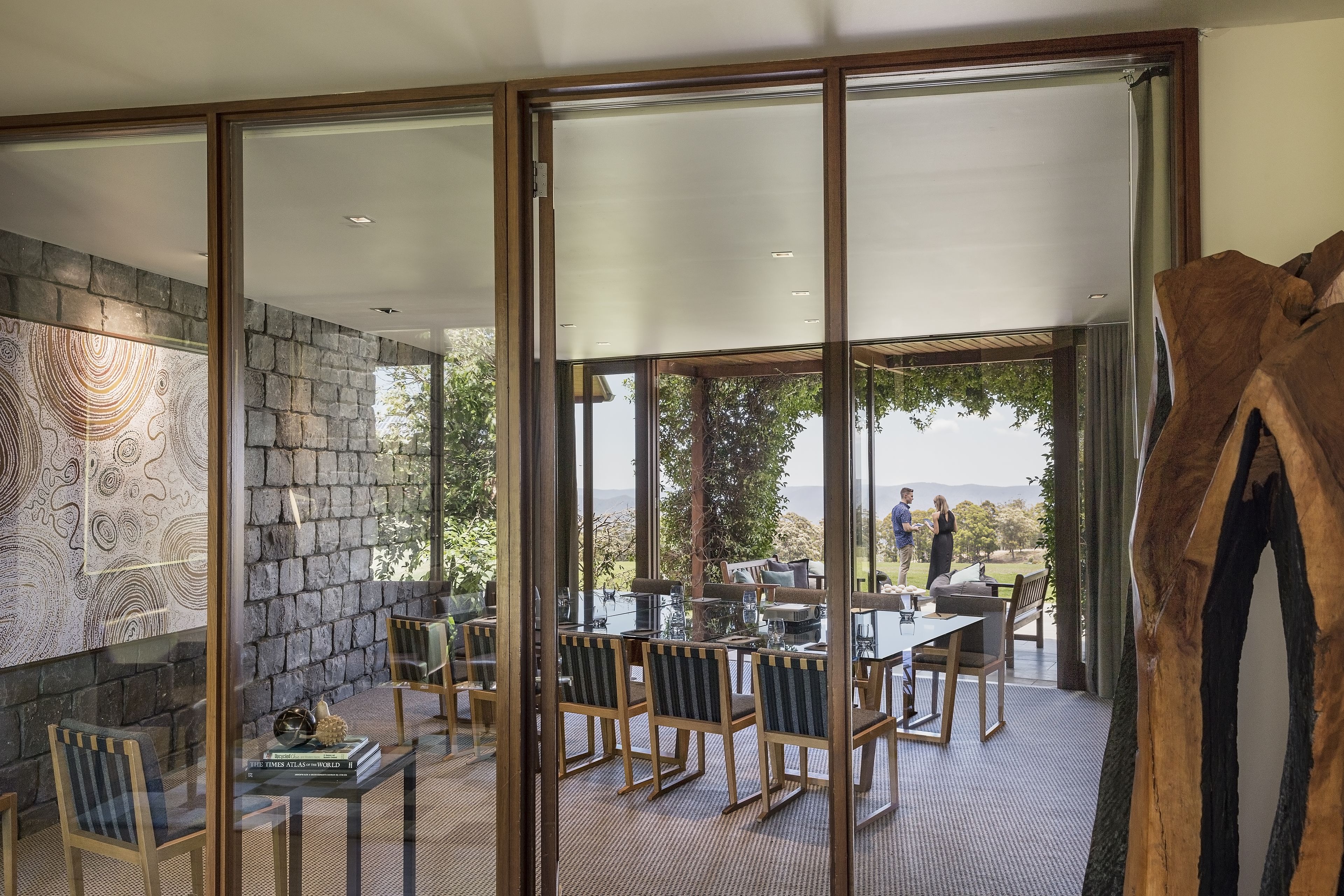 Un comedor moderno con paredes de vidrio, paredes de piedra y vistas al exterior.