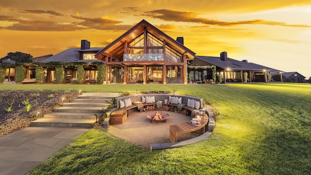 A large, modern house with a spacious outdoor seating area and a well-maintained lawn. - Spicers Peak Lodge (Swanfels)