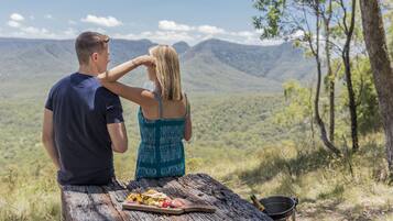 Un couple est assis sur un banc en bois, face à un paysage montagneux.