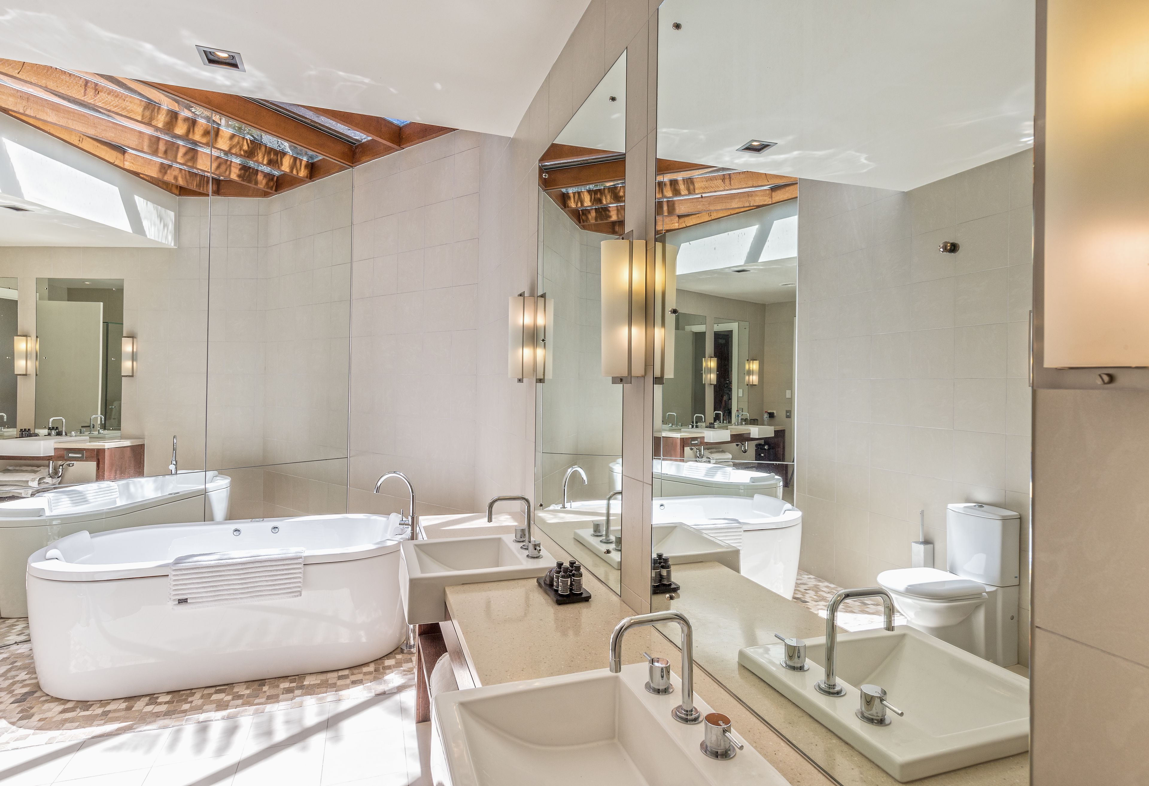 A modern bathroom with a large bathtub, multiple sinks, and a large mirror.