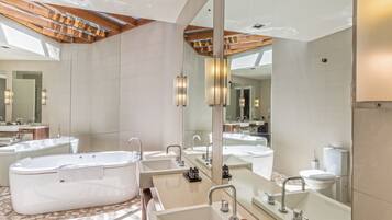 A modern bathroom with a large bathtub, multiple sinks, and a large mirror.