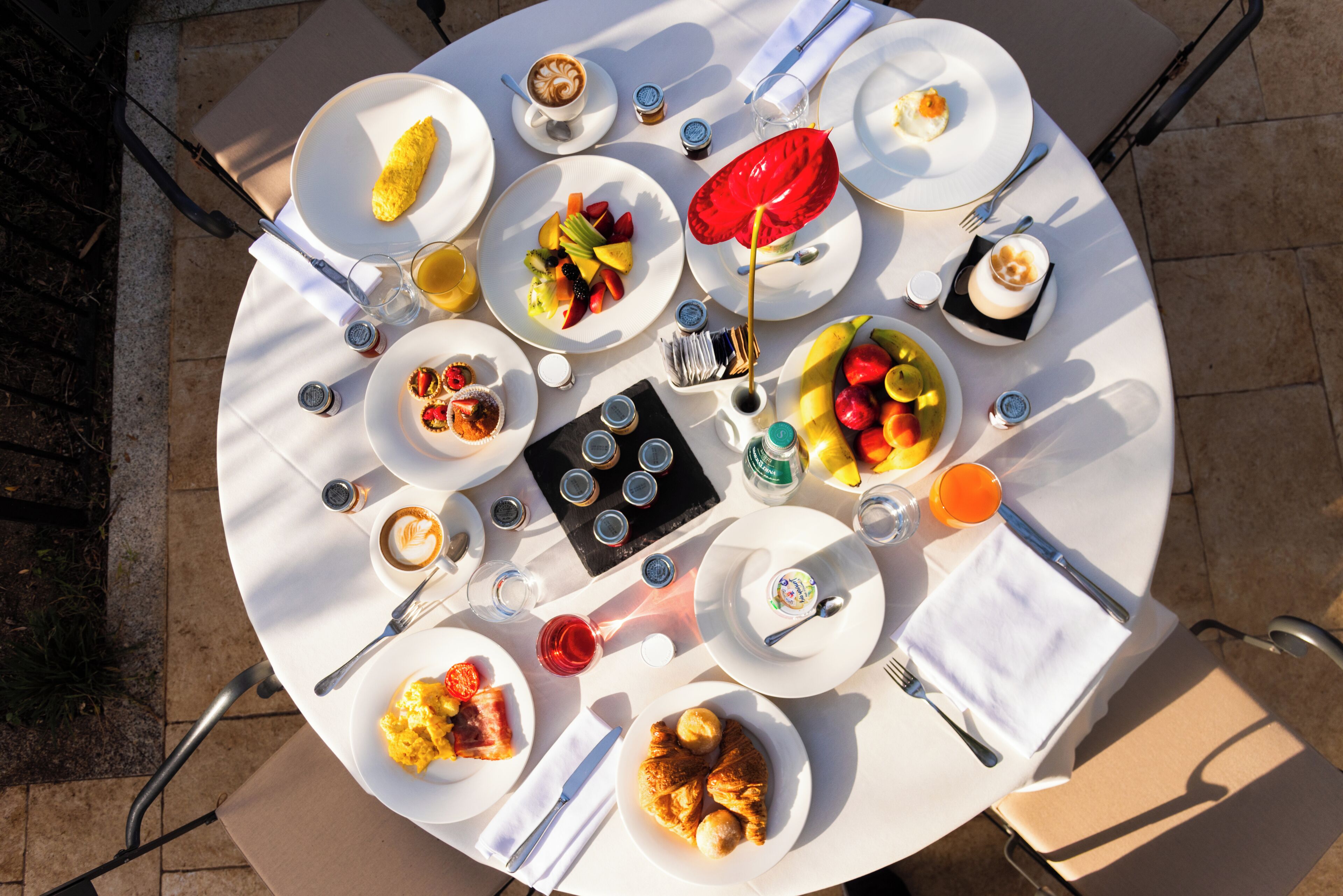 Una mesa redonda con diversos platos, incluyendo frutas, pasteles y un paraguas rojo.
