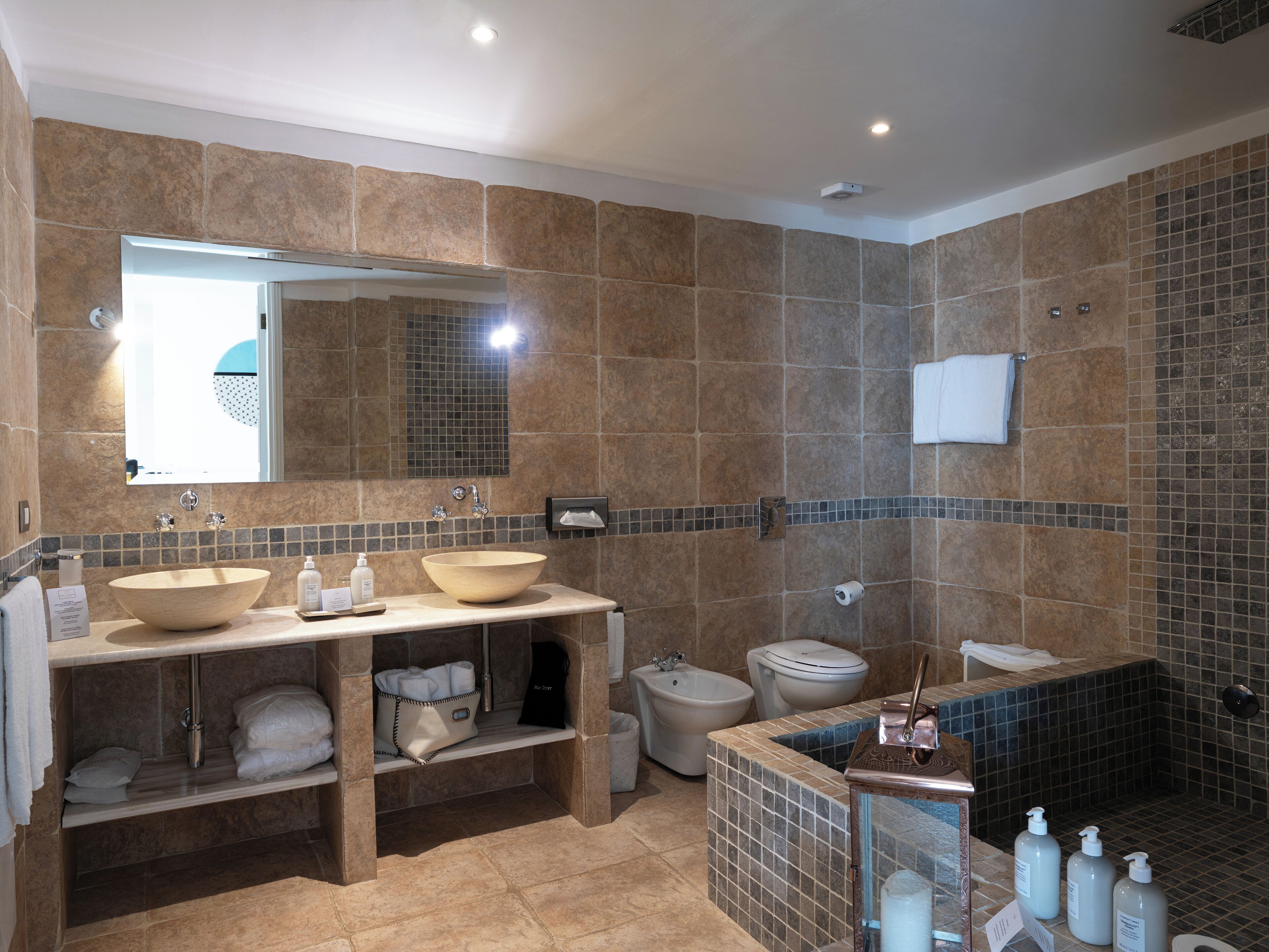 Un bagno moderno con un lavandino ampio, due specchi, un bidet e una zona doccia.
