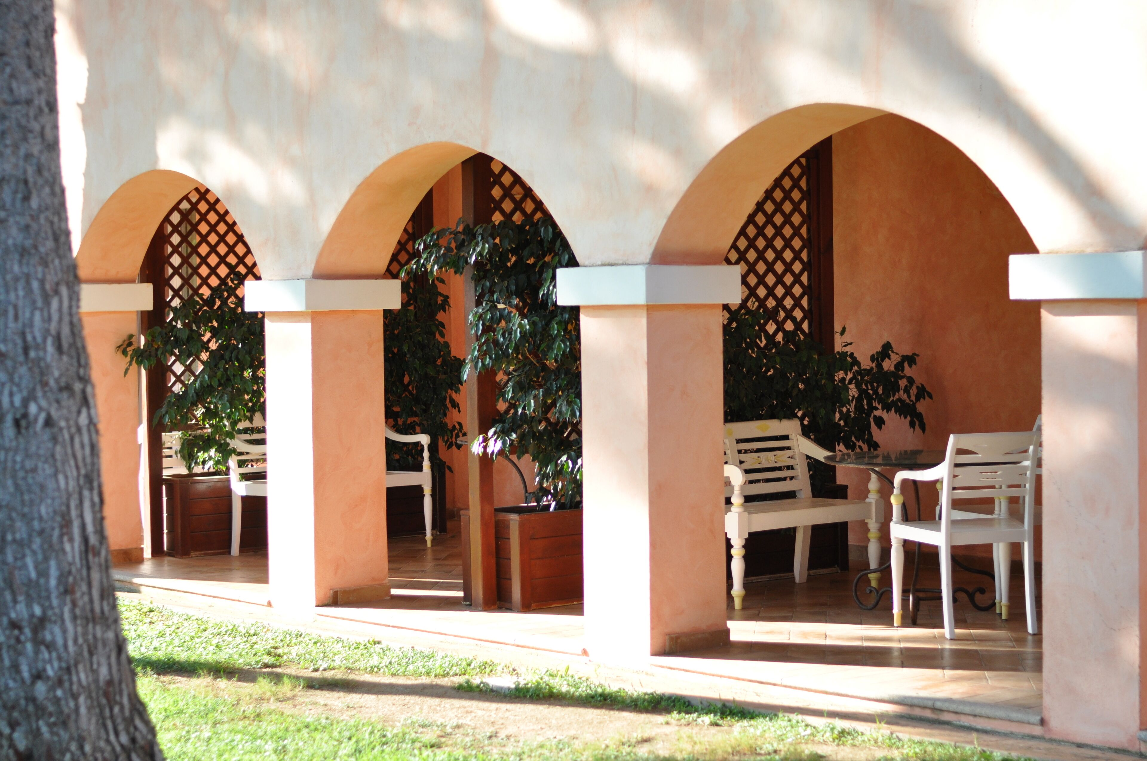 A covered outdoor seating area with arches, tables, and chairs.