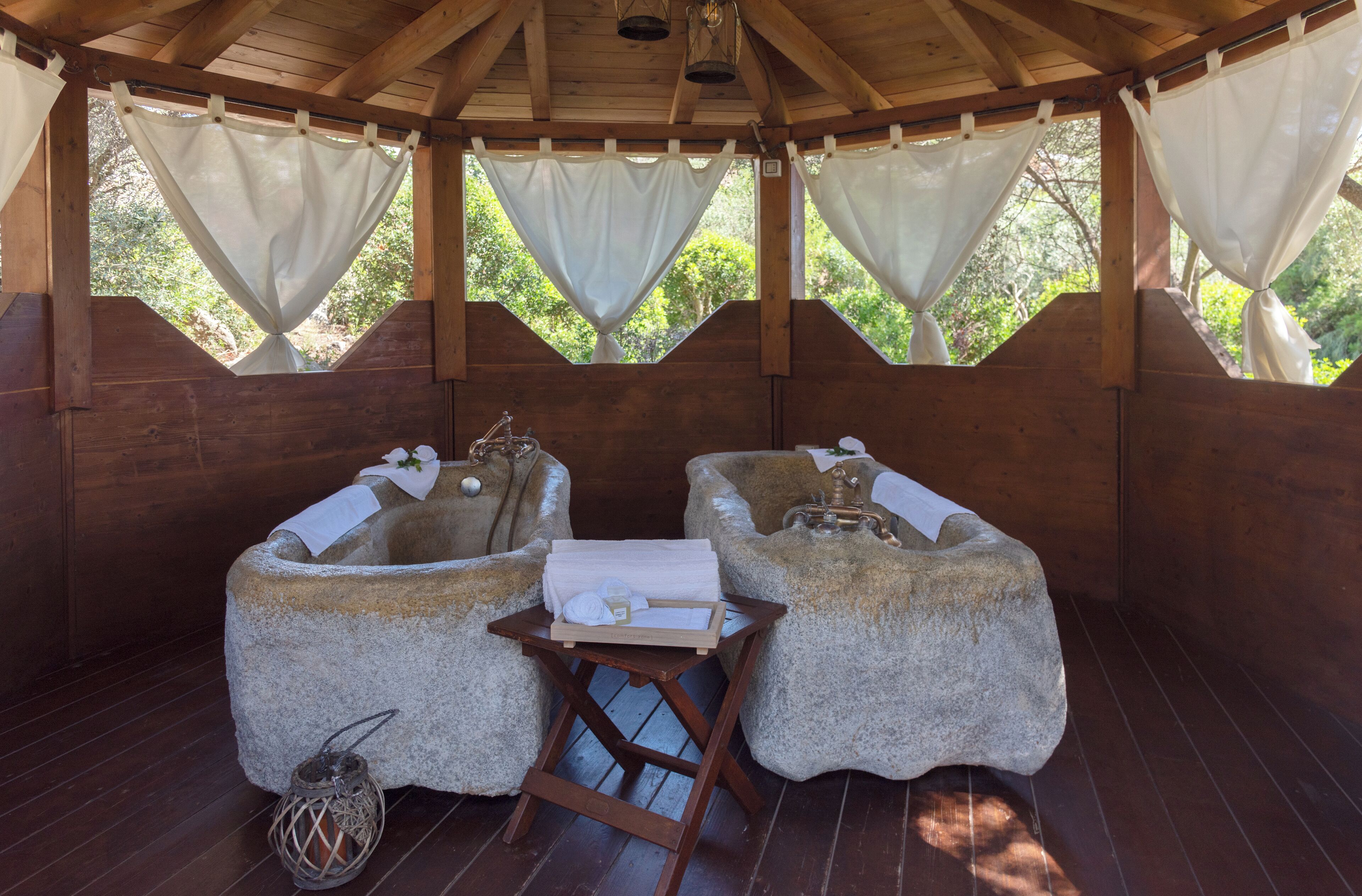 Una cabaña de madera con tinas de piedra y una pequeña mesa con toallas.