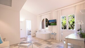 Un espacio habitable amplio con un gran ventanal, un sofá blanco, una mesa de centro y una mesa de comedor blanca con sillas.
