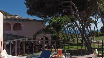 Un patio al aire libre con una mesa redonda, sillas blancas y una computadora portátil.