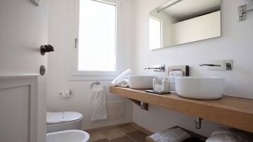 Ein modernes Badezimmer mit Toilette, Waschbecken und Spiegel sowie einem Fenster, das für natürliches Licht sorgt.
