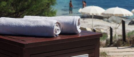 Una caja de madera con un letrero que indica 'Clean beach towels' y 'Teli spiaggia puliti'.