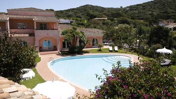 Un complexe hôtelier doté d’une piscine, de chaises longues et offrant une vue sur un paysage montagneux.