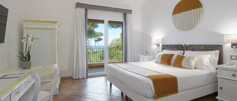 A bedroom with a bed, a desk, and a chair. There is a window with a view of the outdoors.