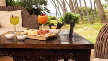 A wooden table with a breakfast spread including a plate of food, two drinks, and bowls.