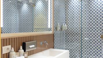Une salle de bain moderne avec un grand miroir, deux vasques, une douche à l’italienne en verre et des carreaux décoratifs.