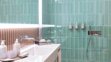 Un bagno moderno con un mobile vanitario bianco, un box doccia in vetro e pareti rivestite di piastrelle verdi.