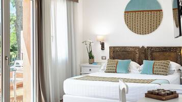 Habitación de hotel con cama, mesita de noche, lámpara y vistas al exterior.