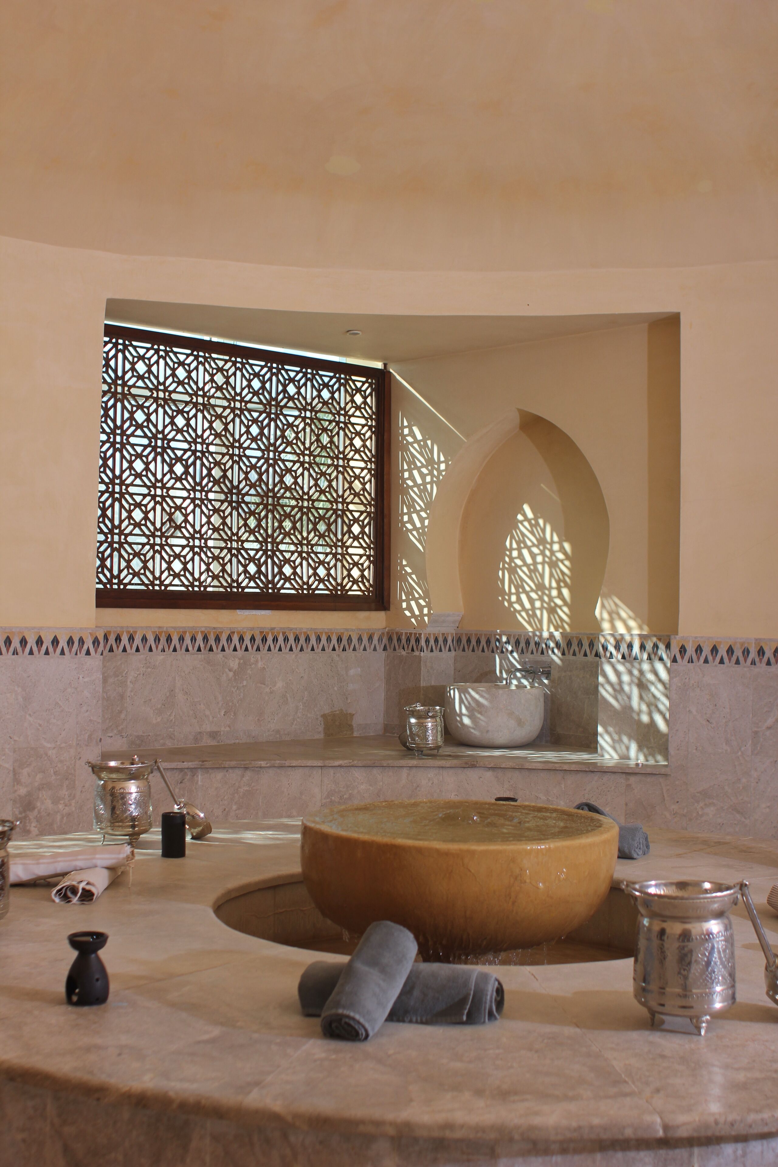 Un baño con una bañera grande, un espejo y una ventana con un panel decorativo.