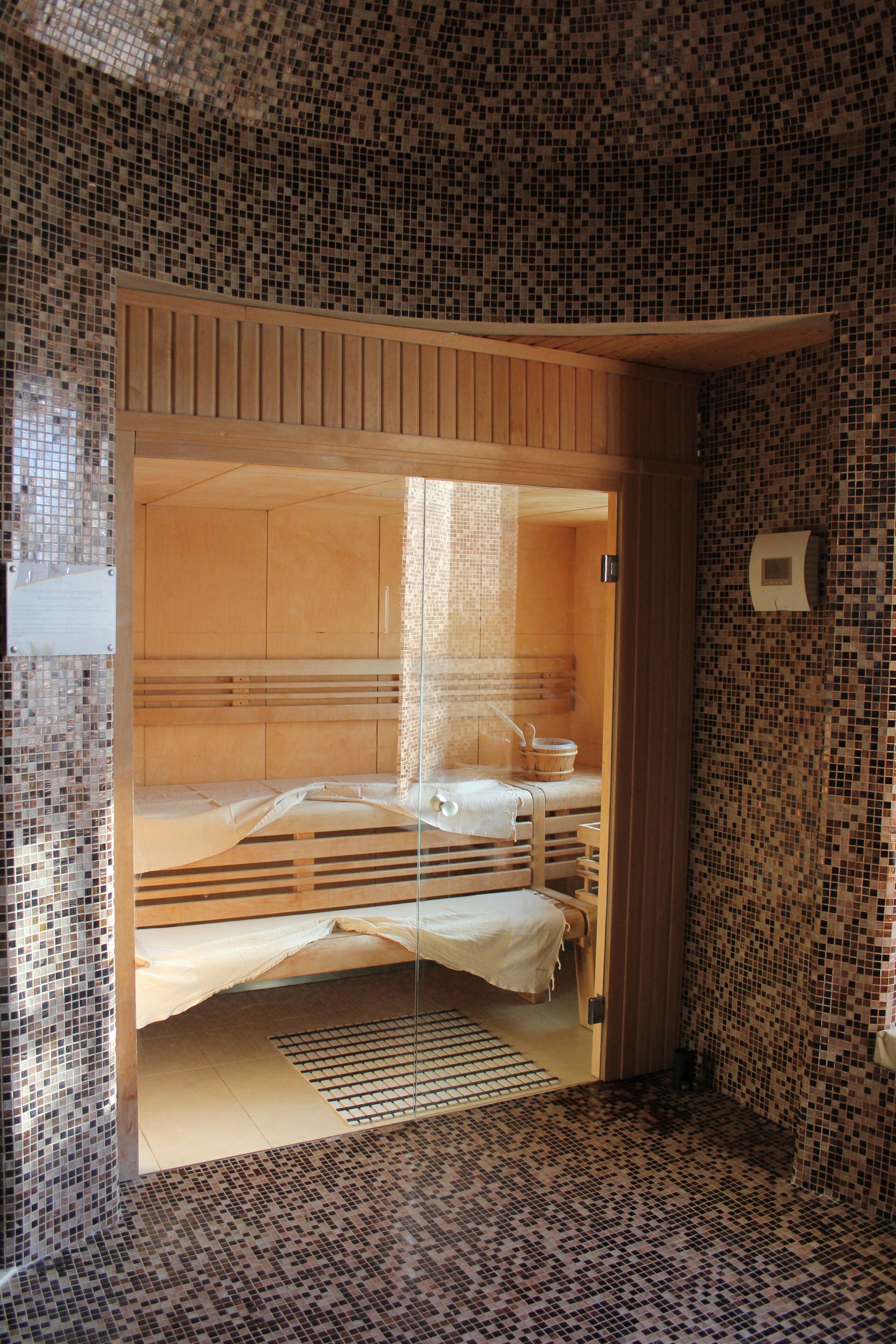 A small, tiled room with a wooden bench and a single bed.