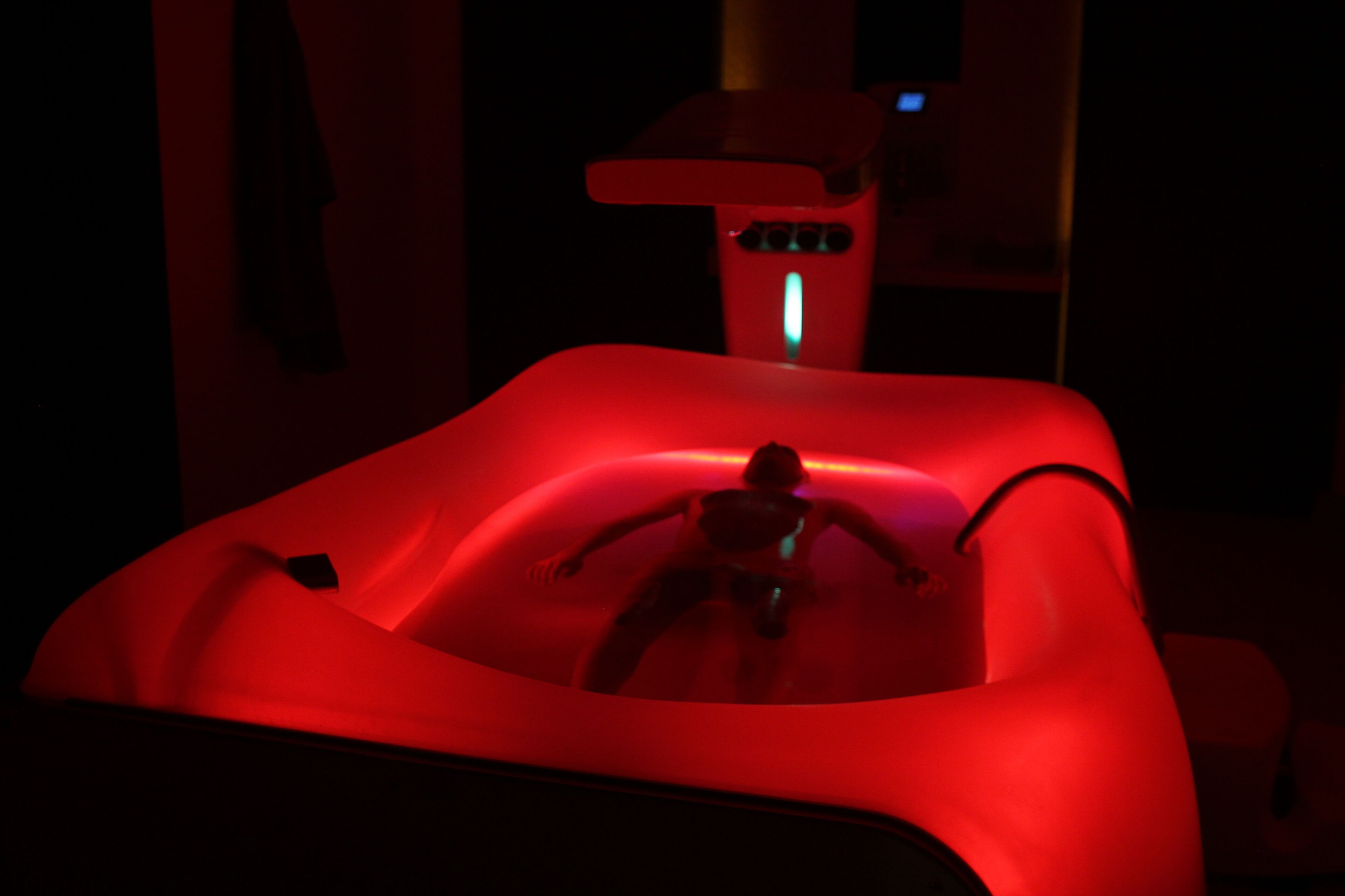 Een kamer in rood licht met een enkel bed en een nachtkastje.