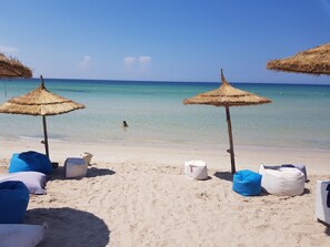 En la playa, sillas reclinables de playa, sombrillas, toallas de playa