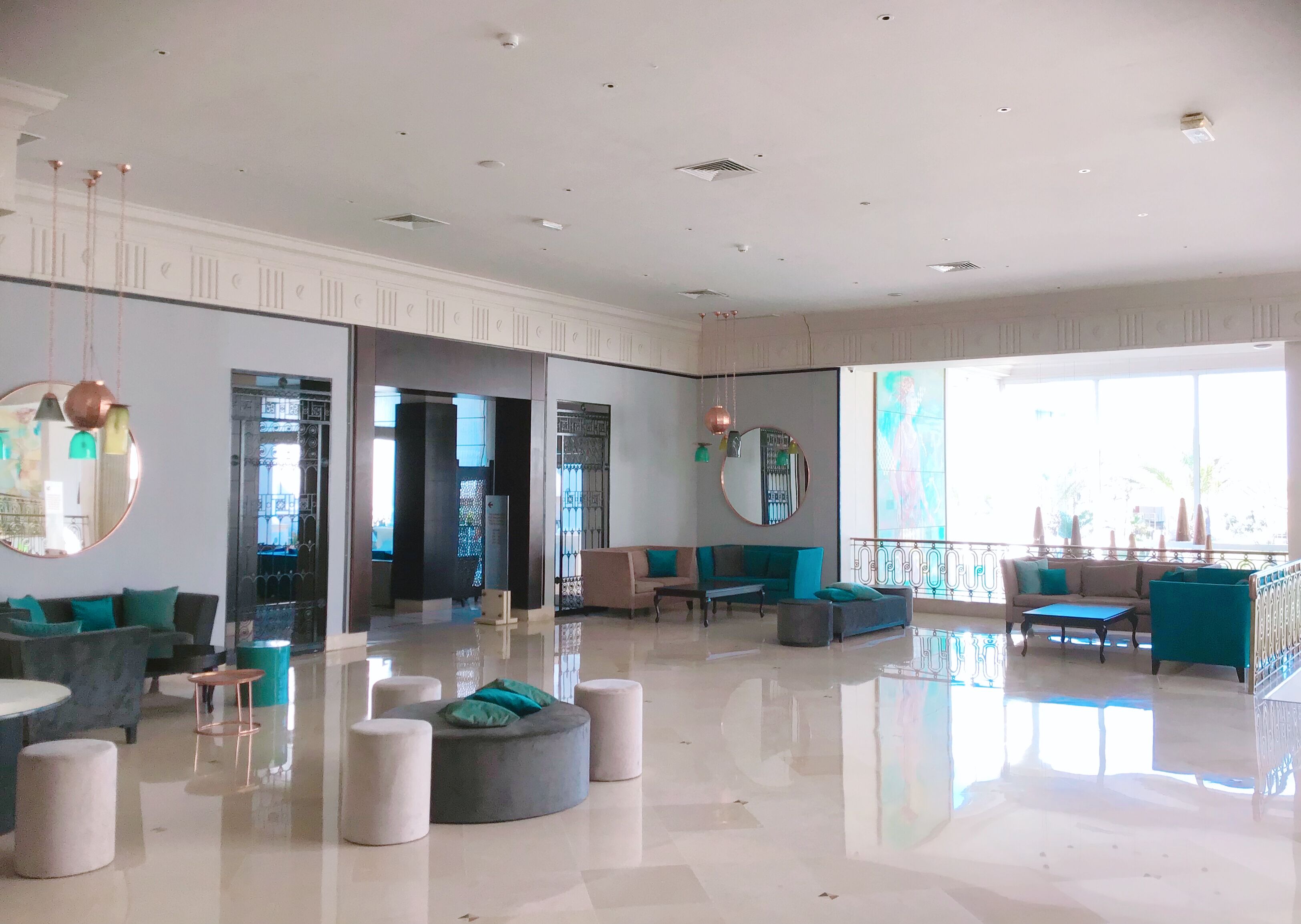 A spacious lobby with a high ceiling, modern furniture, and large windows allowing natural light.