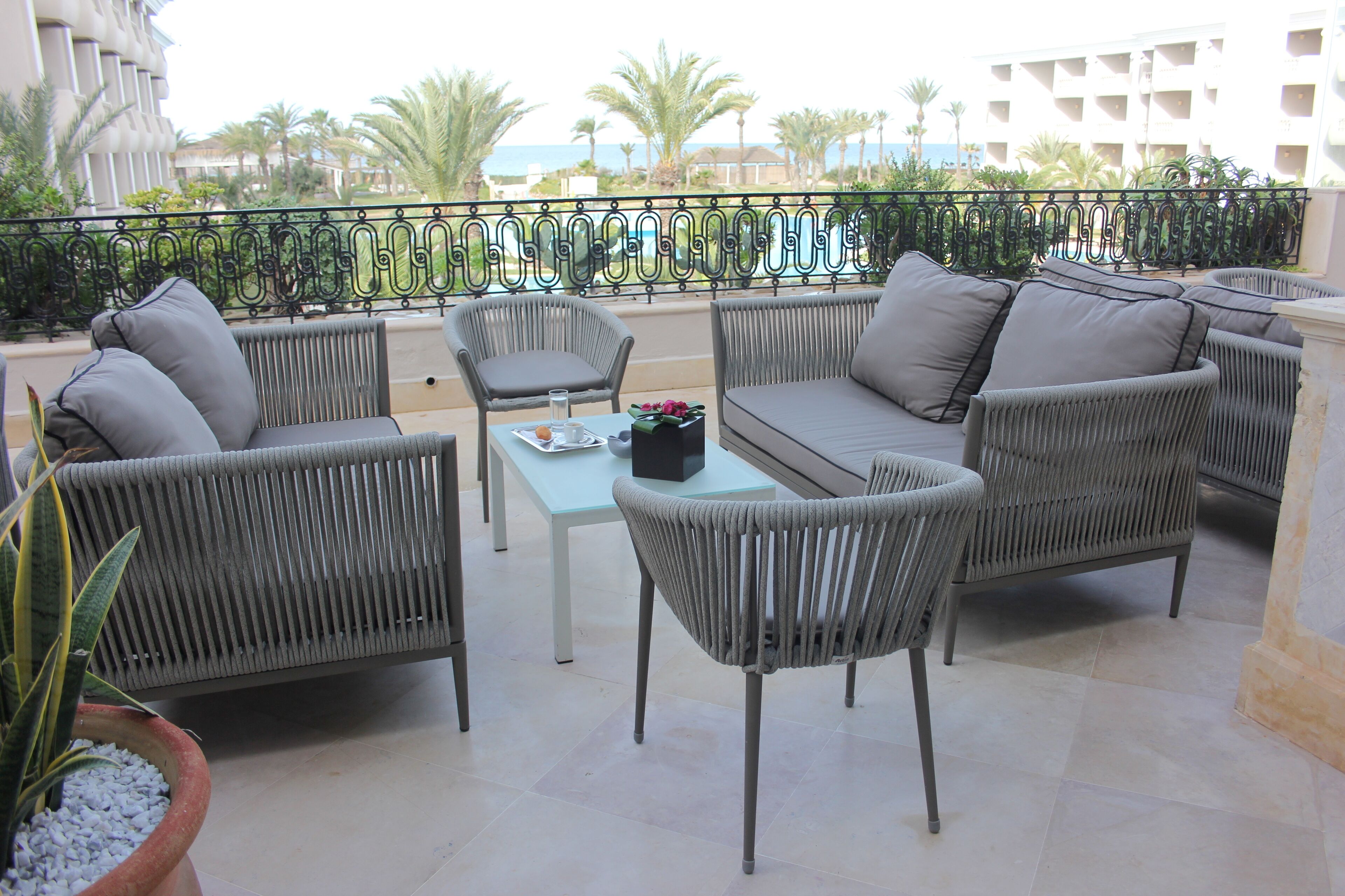 A balcony with wicker furniture, a table, and a potted plant.