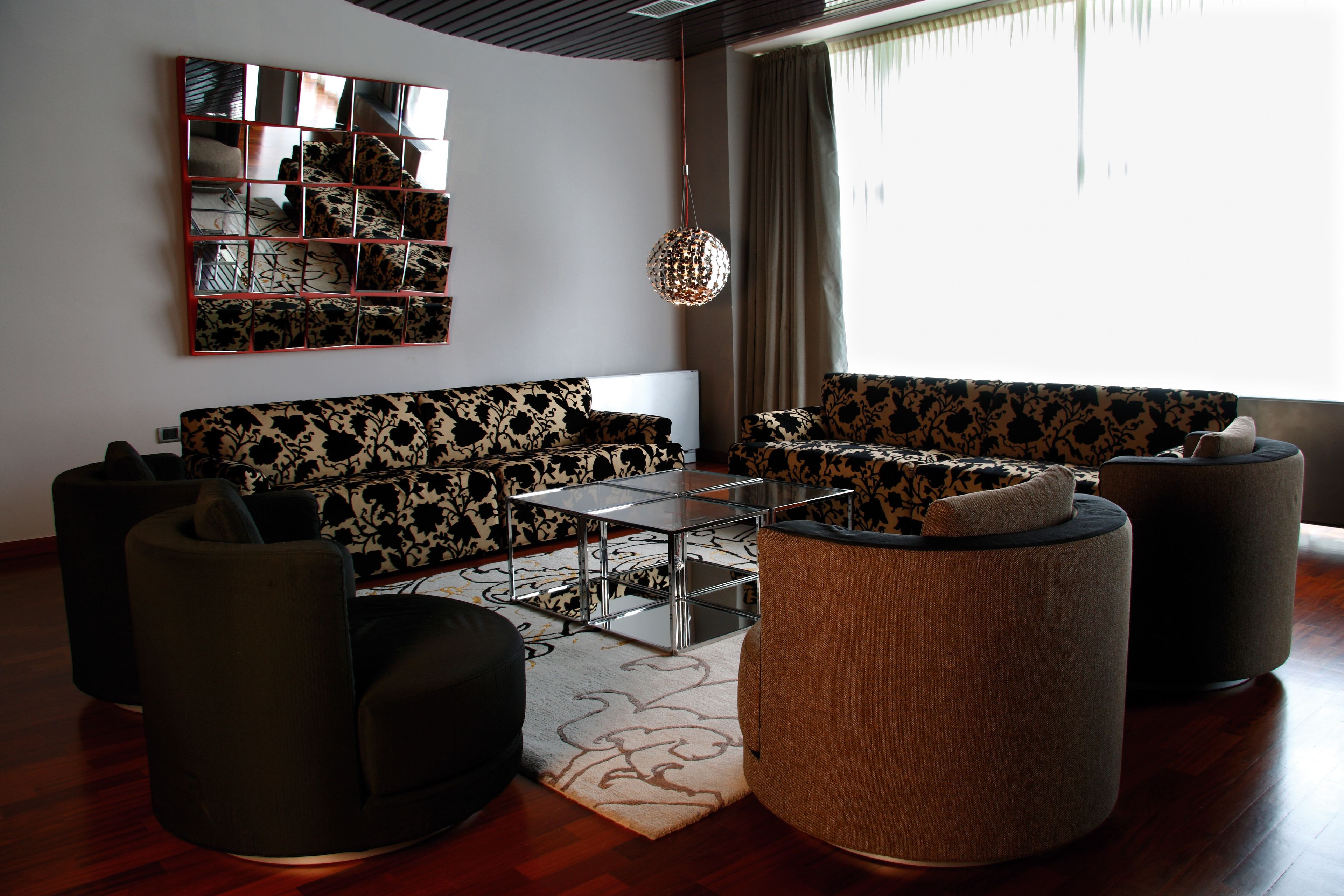 A modern living room with a sectional sofa, a coffee table, and round ottomans.