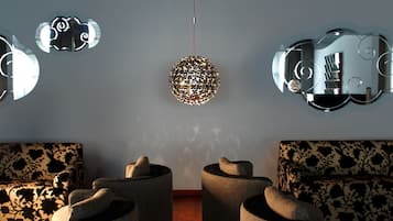 Ein modernes Wohnzimmer mit drei runden, strukturierten Sofas, die halbkreisförmig angeordnet sind, einer dekorativen, kugelförmigen Leuchte und einem wandmontierten Spiegel mit rundem Rahmen.