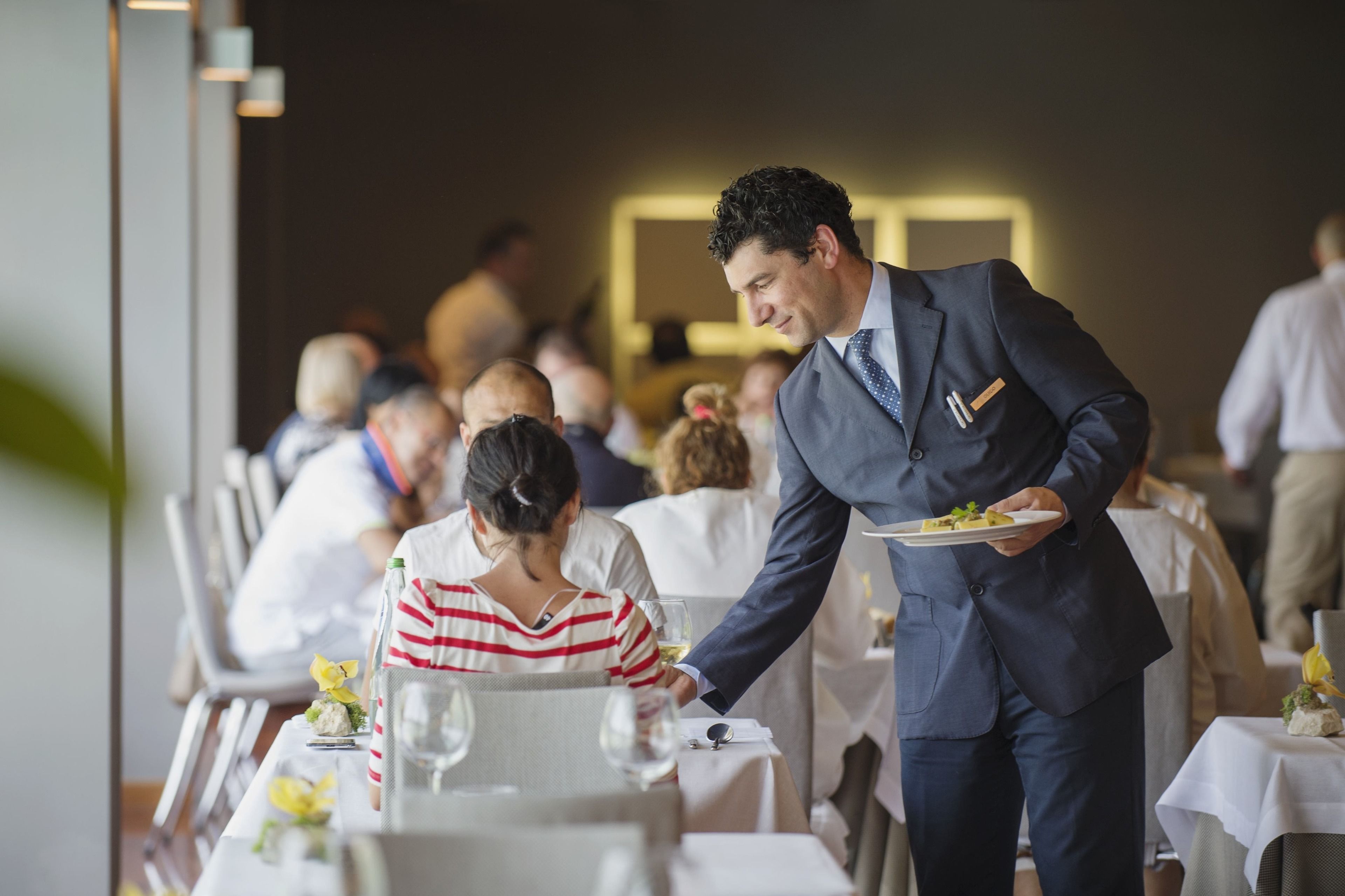 Un cameriere serve un pasto a un tavolo in un ristorante.