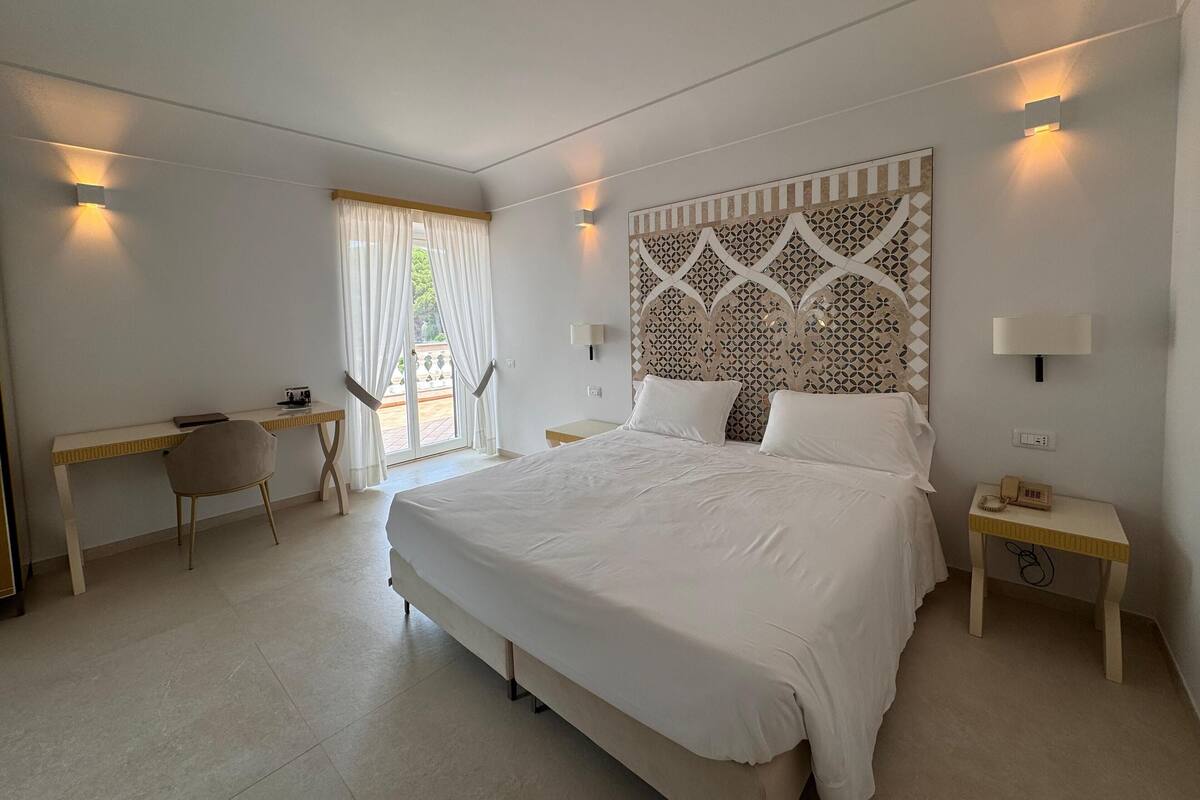 A modern hotel room with a large bed, a desk, and a chair.