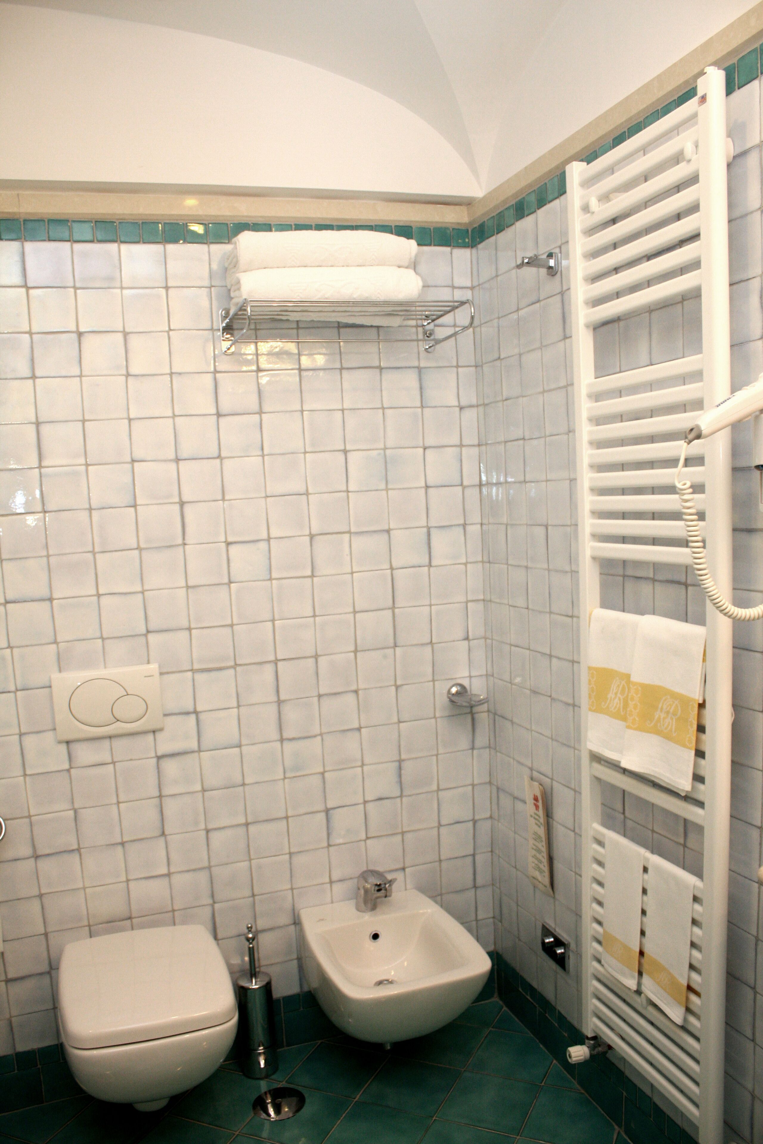 A bathroom with a toilet, bidet, and a towel rack.