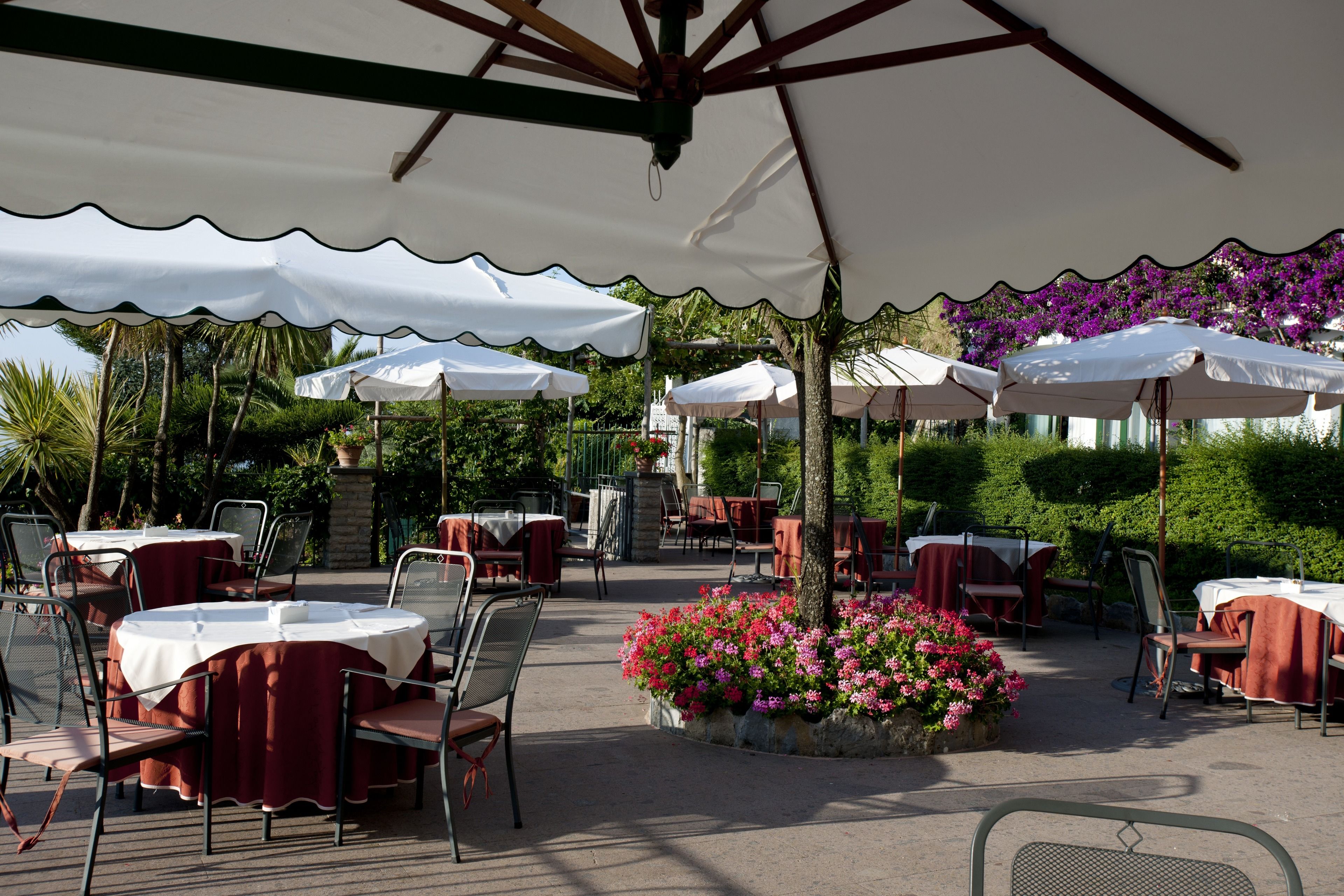 An outdoor dining area with round tables, chairs, and umbrellas.