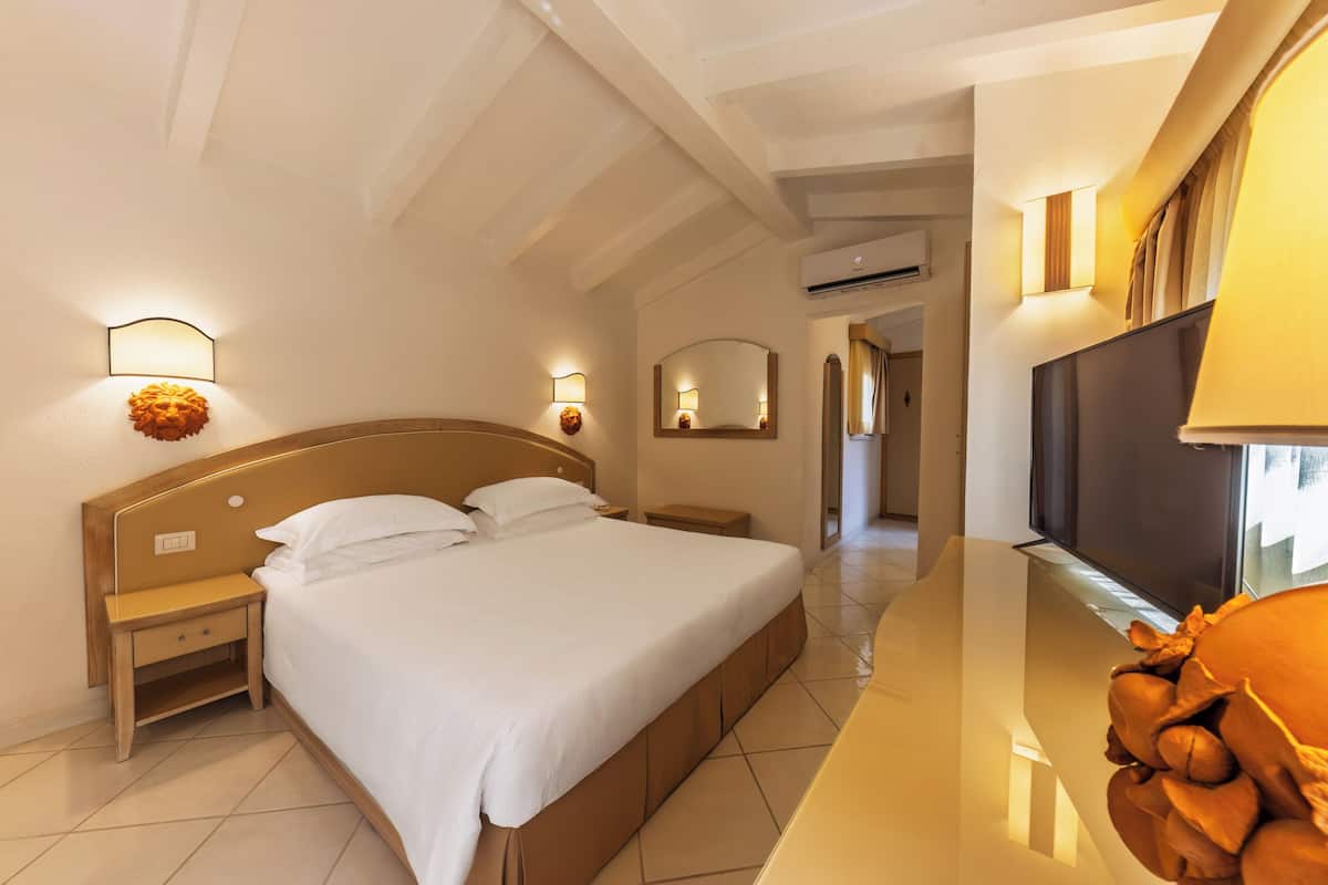 Ein Hotelzimmer mit Bett, Nachttischen, Fernseher und Wandleuchten.