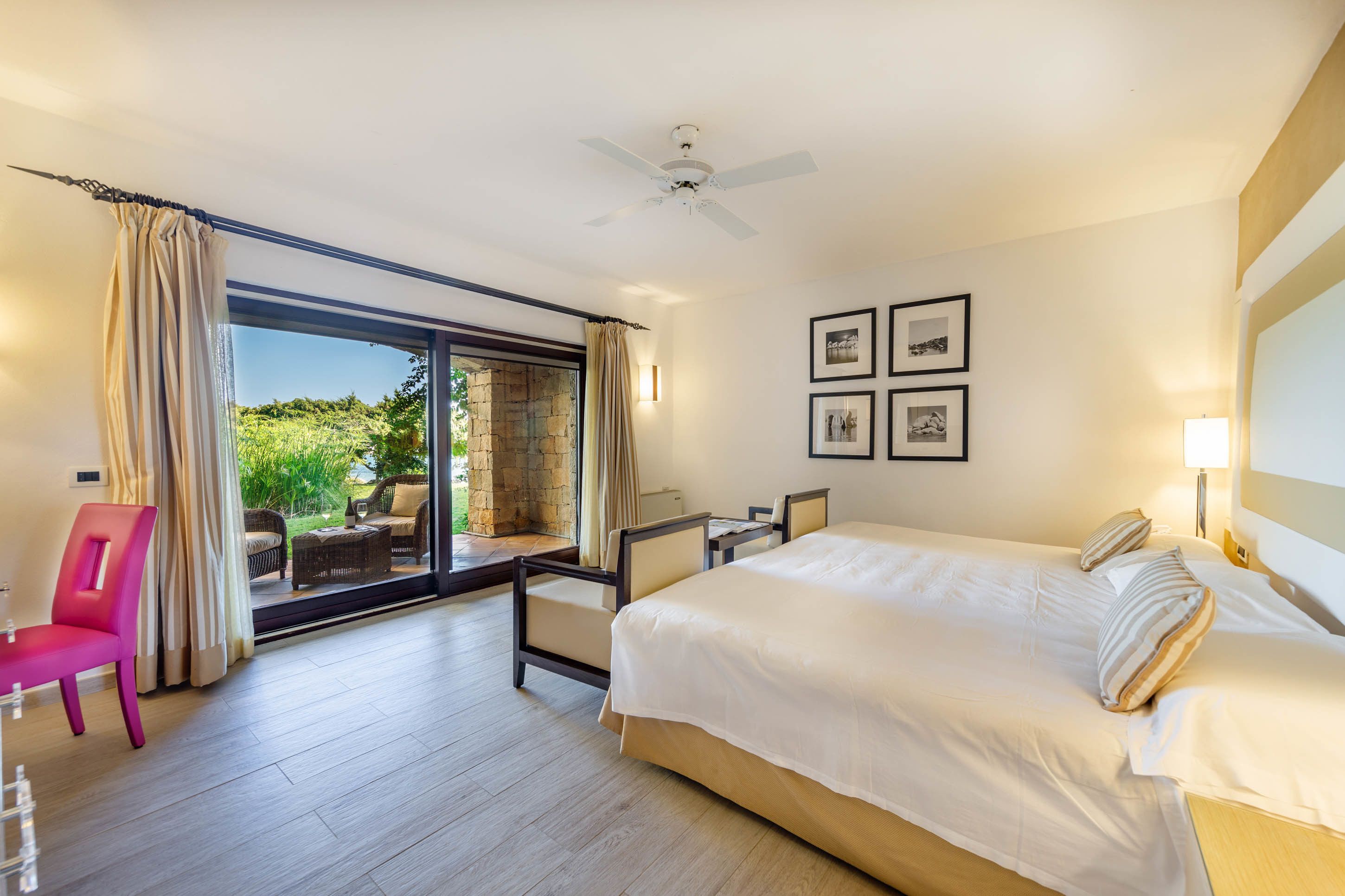A hotel room with a large bed, a desk, a chair, and a view of the outdoors.