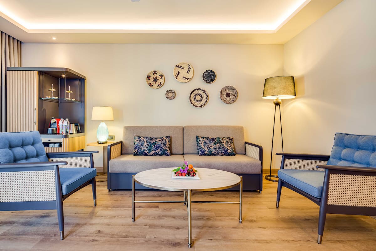 Una sala de estar moderna con un sofá, dos sillones, una mesa de centro y platos decorativos en la pared.