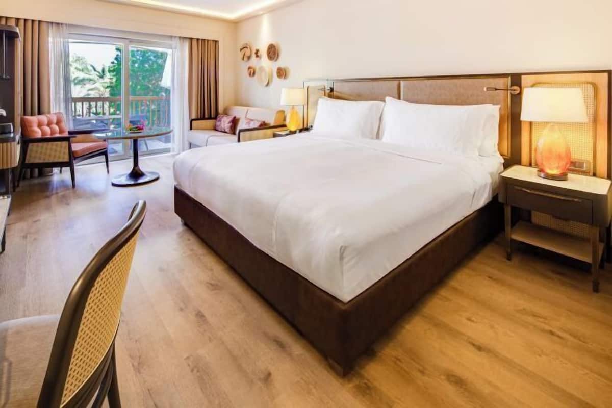 Habitación de hotel con una cama grande, un escritorio con una silla, una mesita y una lámpara.