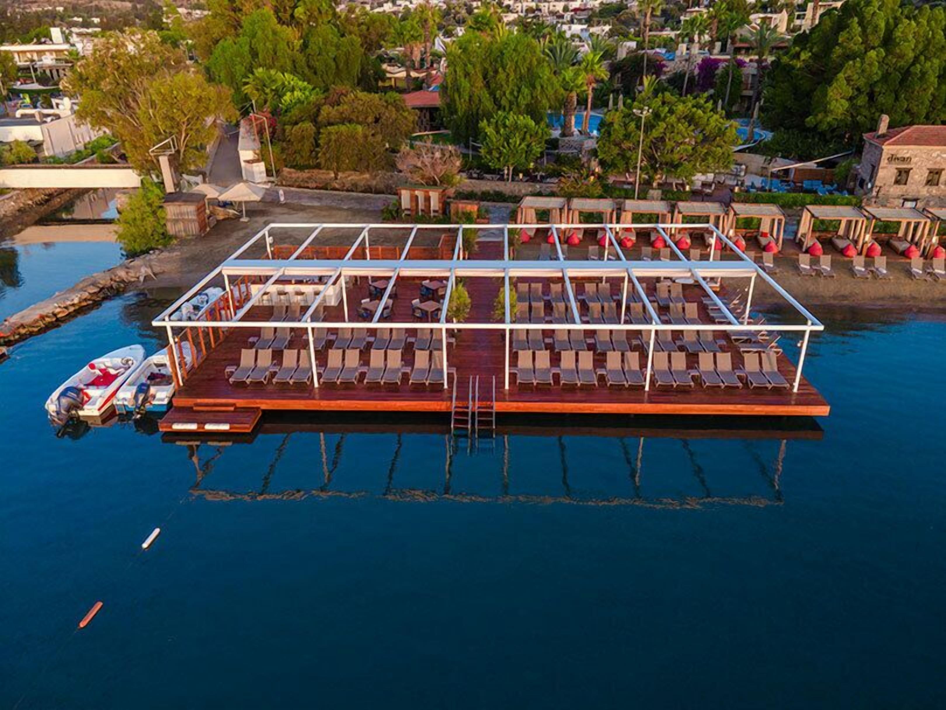 A floating structure with multiple sun loungers and a small boat docked nearby.