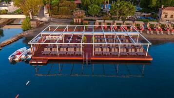 A floating structure with multiple sun loungers and a small boat docked nearby.