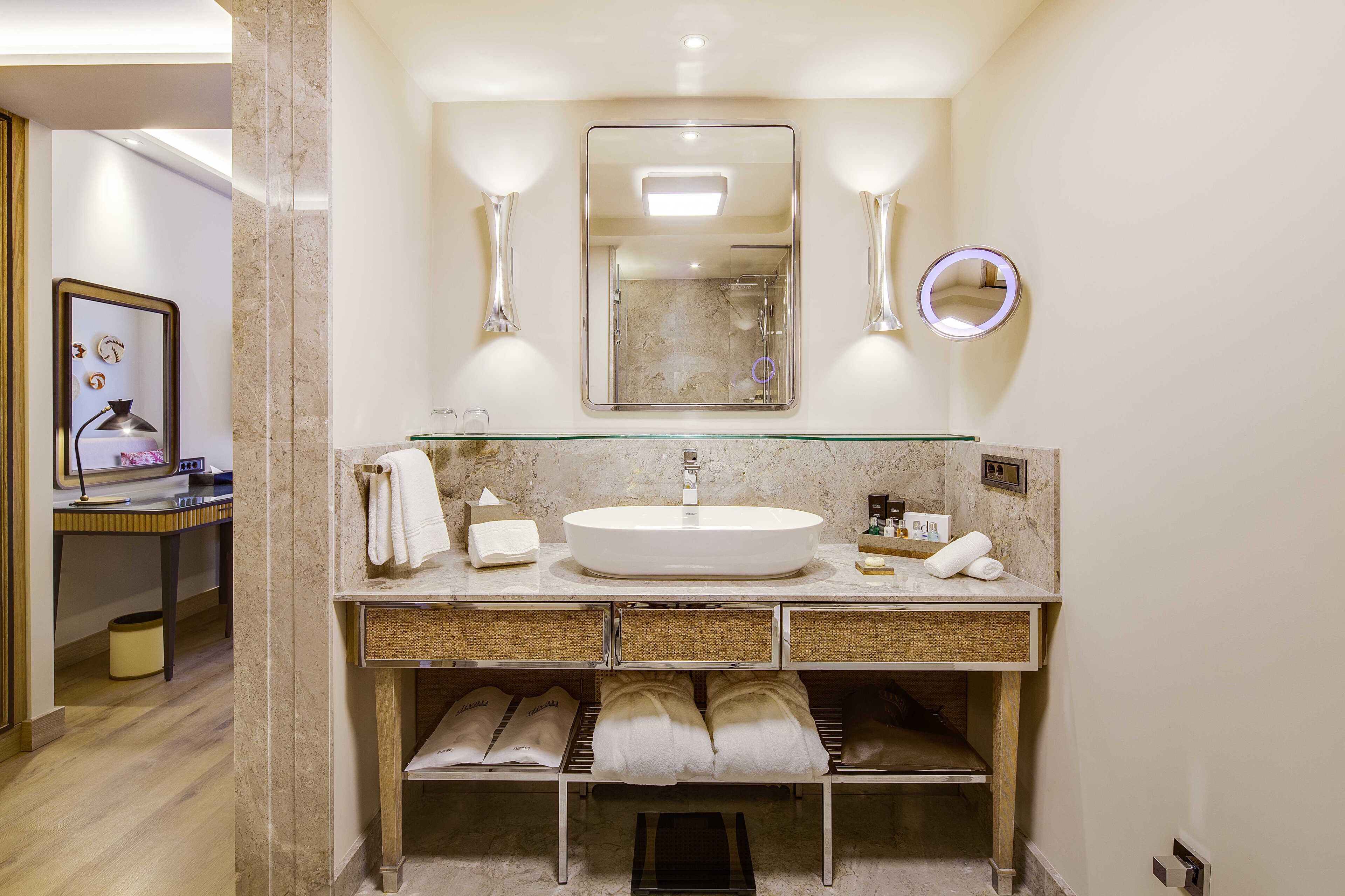 A modern bathroom with a large mirror, a round mirror, and a glass-enclosed sink.