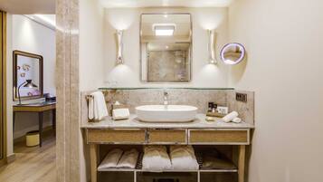 A modern bathroom with a large mirror, a round mirror, and a glass-enclosed sink.