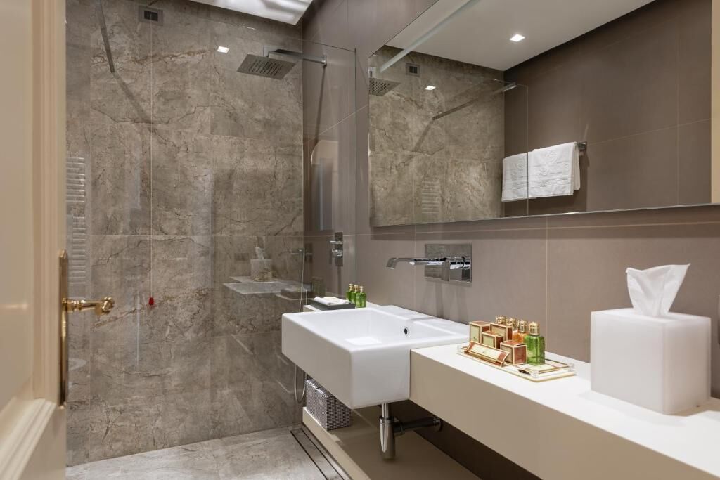 Une salle de bain moderne avec une douche à parois de verre, un lavabo blanc et un meuble-lavabo avec des articles de toilette.