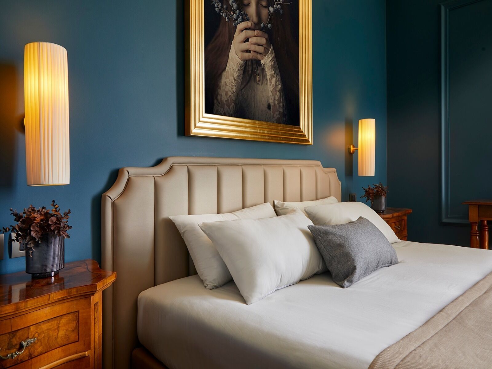 Camera da letto con un letto grande, due comodini, una lampada a parete e un quadro incorniciato sopra il letto.