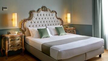 Una cama grande con cabecera capitonada, dos mesitas de noche con lámparas y una manta verde.
