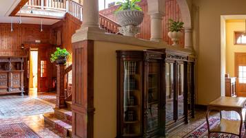 Eine geräumige Lobby mit einer imposanten Treppe, Holzvertäfelung und einem großen Bücherregal.