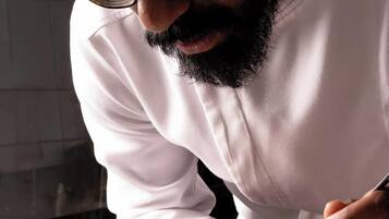 A person in a white shirt serving food on a white plate.