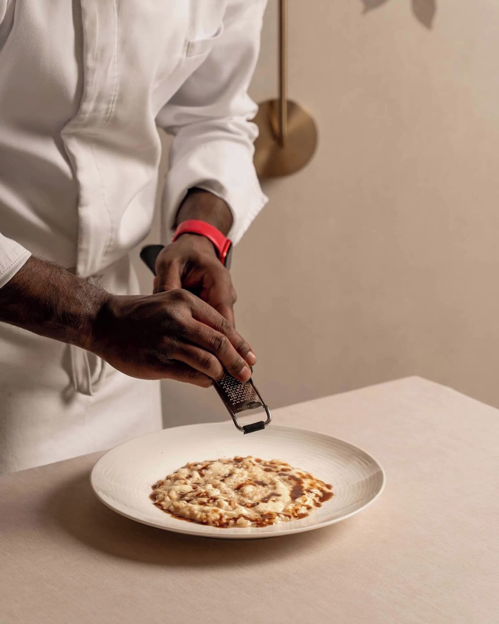 Una persona rallando queso sobre un plato.