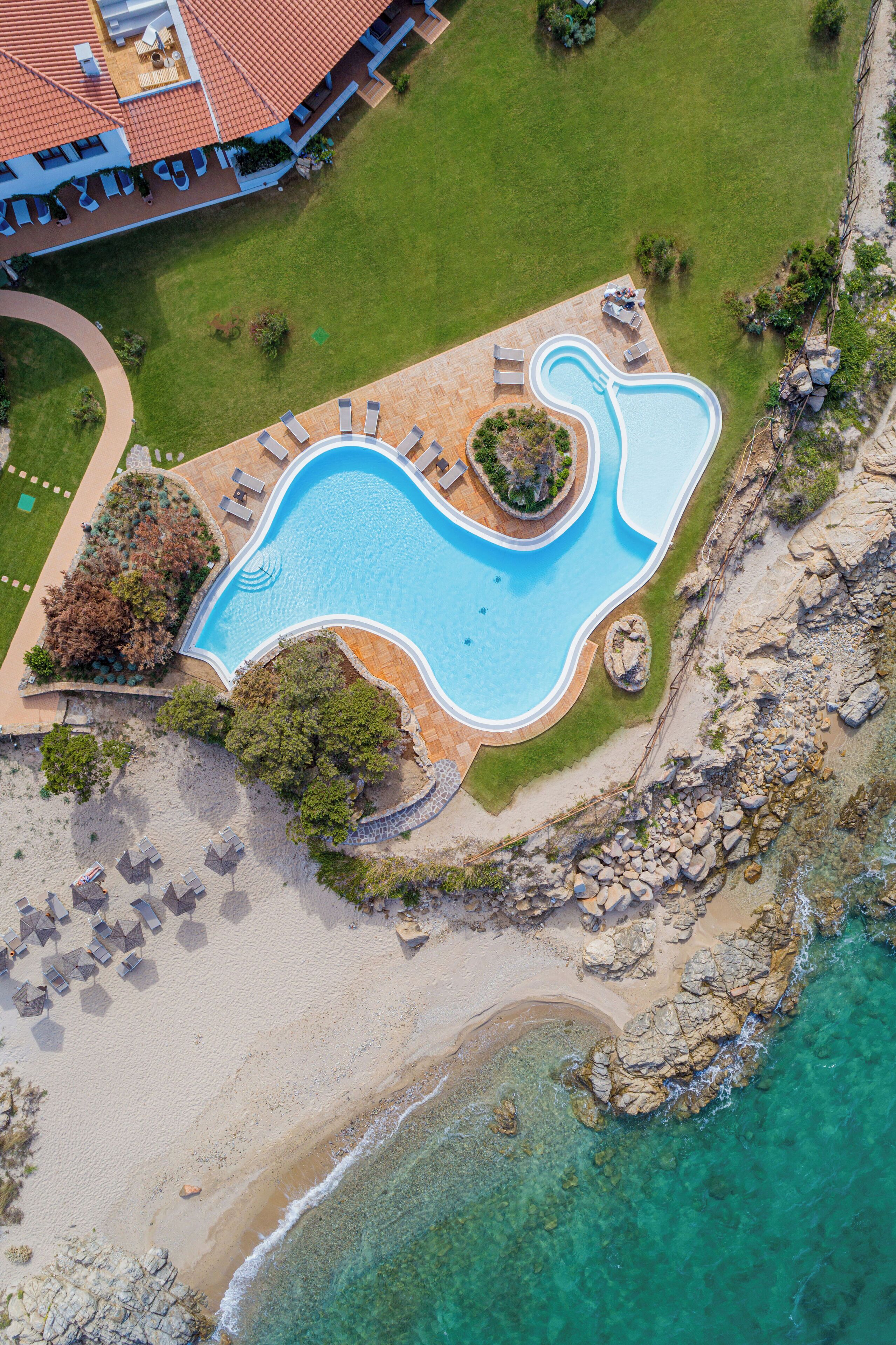 Vista aérea de un complejo turístico con piscina, playa y océano.