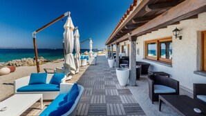 A seaside patio with outdoor seating, a wooden pergola, and a view of the ocean. - Hotel Sporting (Olbia)