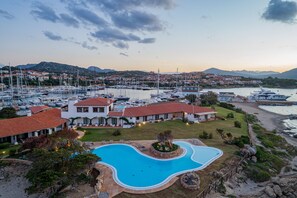 Un hotel frente al mar con piscina, puerto deportivo y vistas al océano.