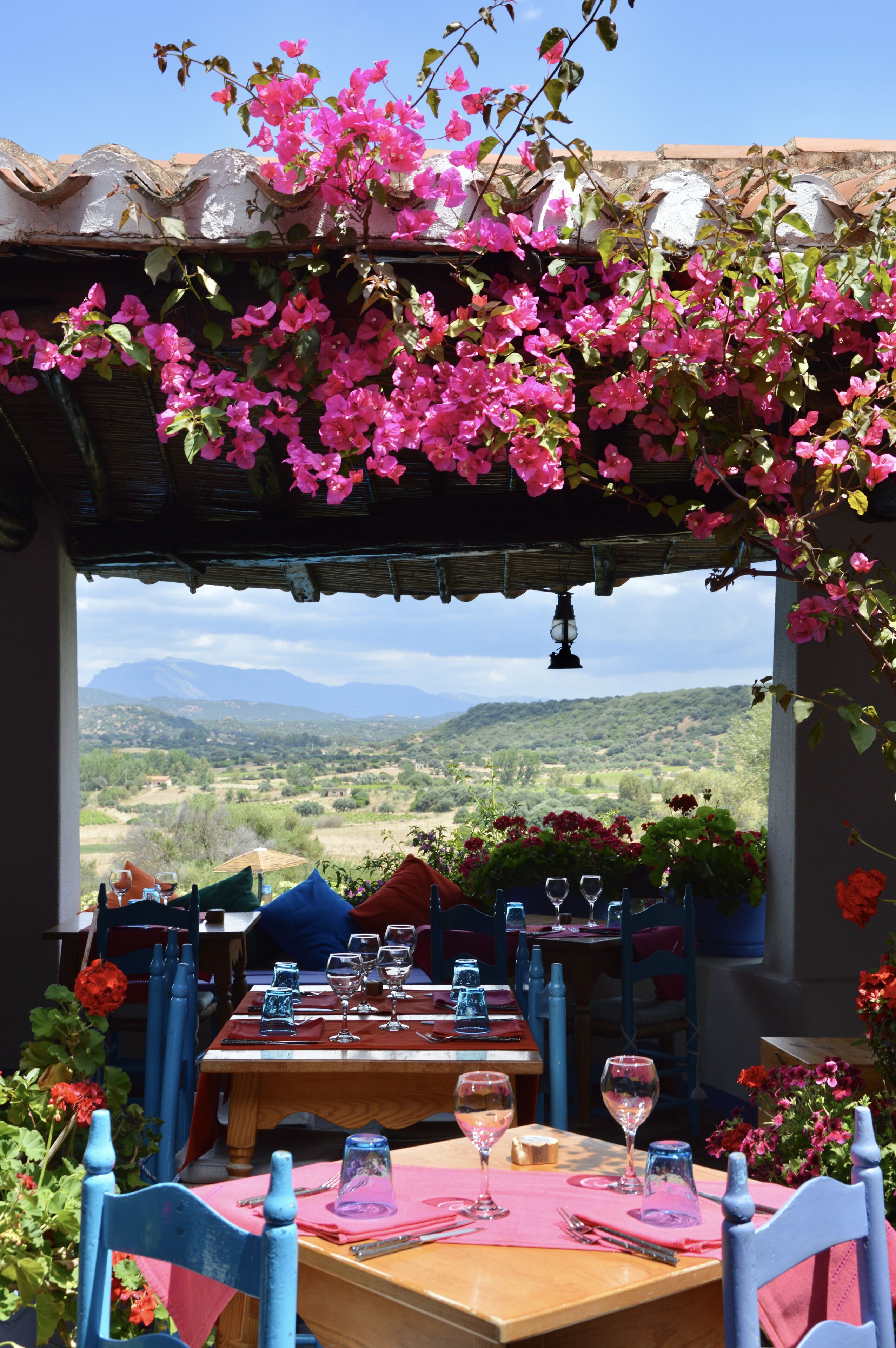Un área de comedor al aire libre con una mesa preparada para dos, con vistas a un paisaje montañoso.